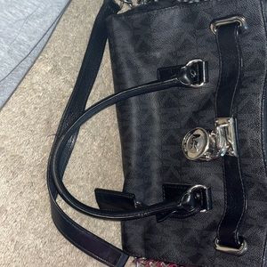 Black Michael Kors luggage style hand bag. Silver buckle with the designer.